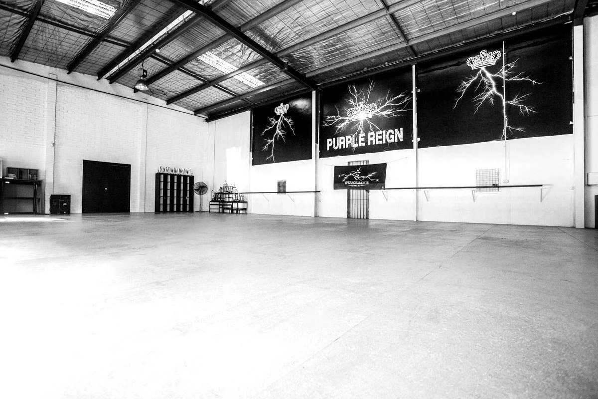 Empty TPC studio interior, Purple Reign signage on the far wall, sprung-floor space ready for class