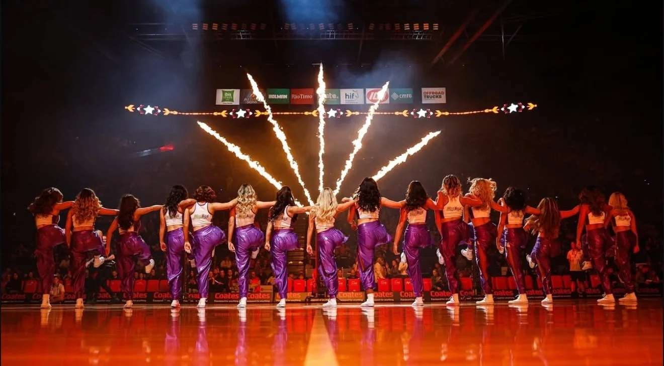 TPC crew in formation onstage, pompoms mid-routine